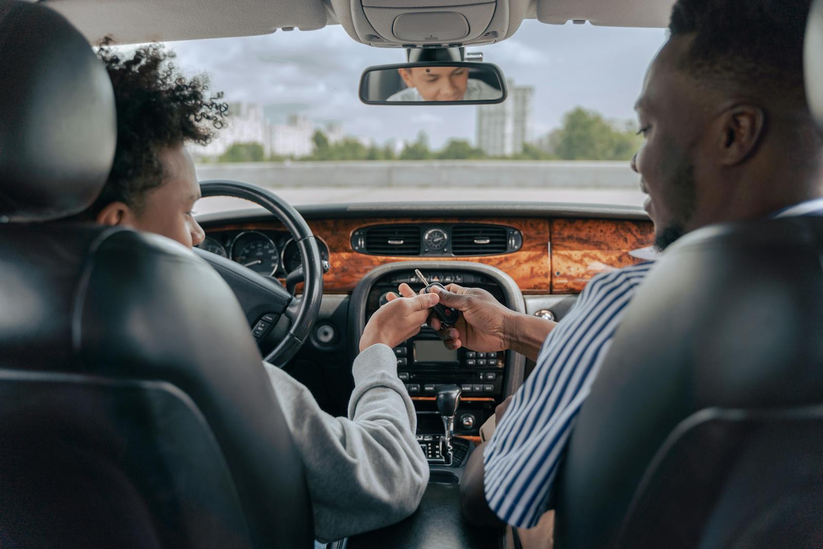 Father and teenage son inside car learning to drive, fostering bonding and guidance.